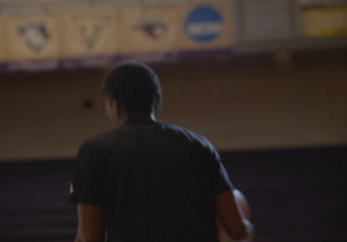A group of men play basketball in an empty basketball court during the day