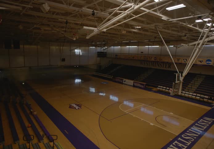 The lights are gradually turned on inside of a gym housing a basketball court