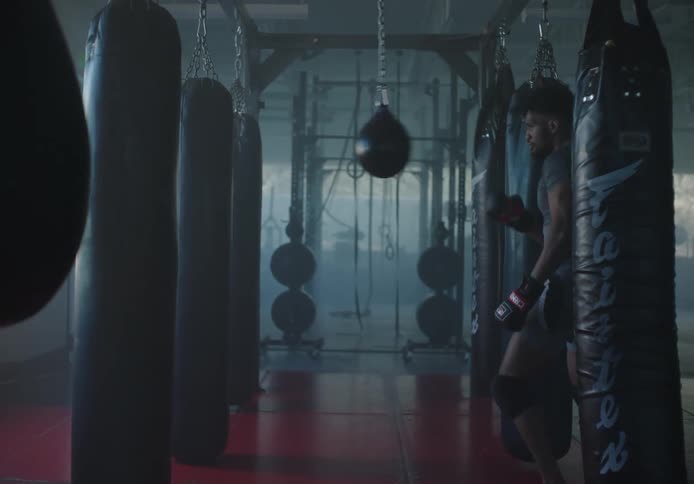 A man punches a speed bag in a gym during the day