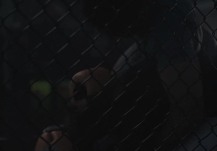 Male combatants fight in behind chain link fence during sports match