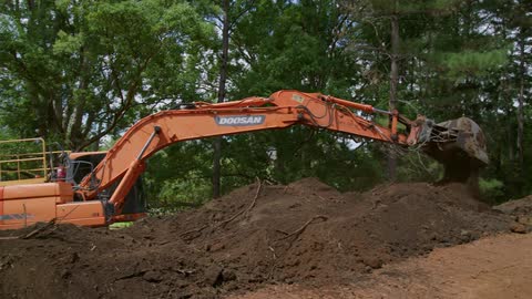 An excavator moves dirt in a field during the day