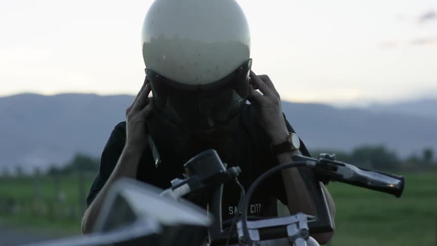 A man puts on his motorcycle helmet