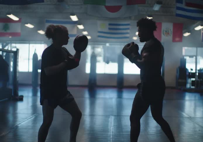 Man and woman wearing boxing gloves practicing boxing in an empty gymnasium