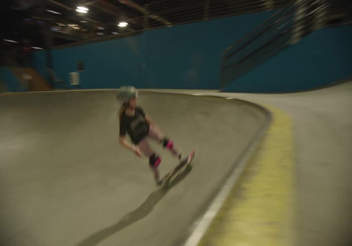 A person performs a trick on a skateboard on a ramp in a skateboard park