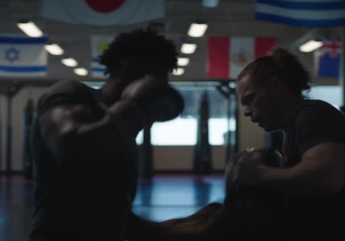 Trainer holds a pad and fighter hits it in boxing gym