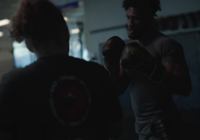 A man is kicking a sparring partner with pads