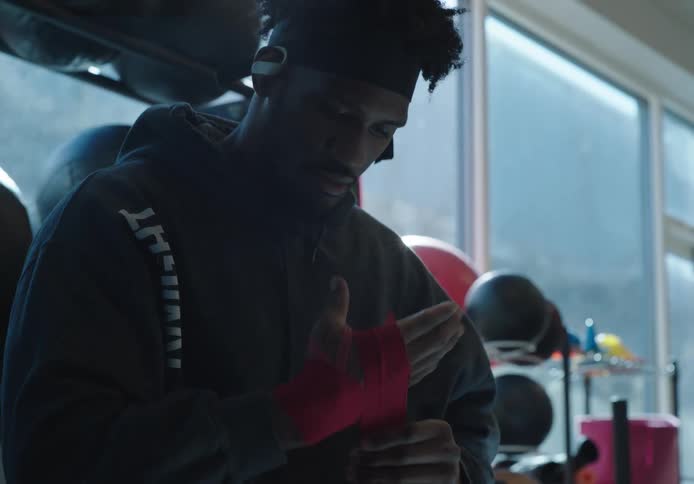 Black man at the gym tying hand wraps on his fist