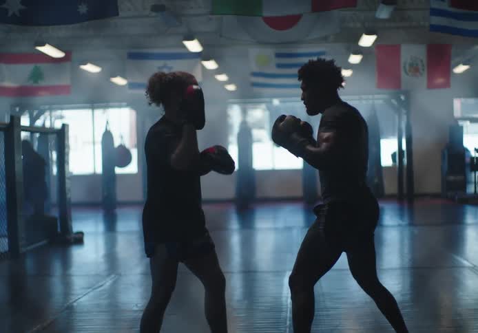 A man wearing boxing gloves practices with a sparring partner