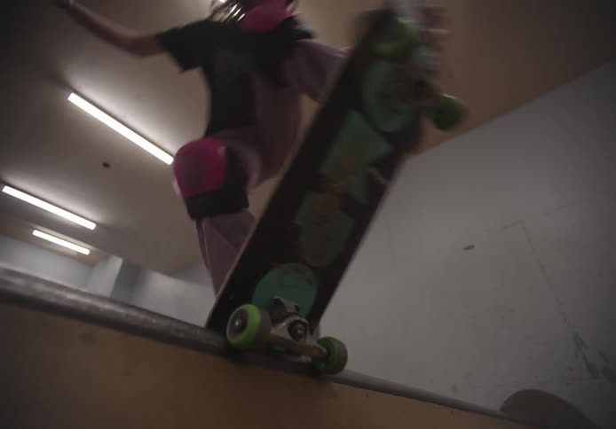 Teenager girl wearing a helmet skateboarding on a ramp indoors