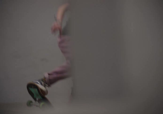 Girl with a safety helmet and knee pads skateboarding at an indoor skate park