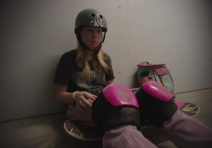 A girl gets up and walks away with her skateboard