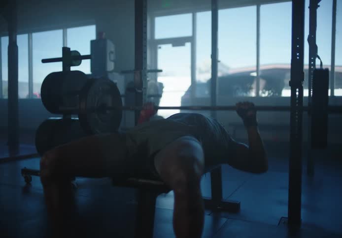 Man in an empty gym doing bench press with heavy weights
