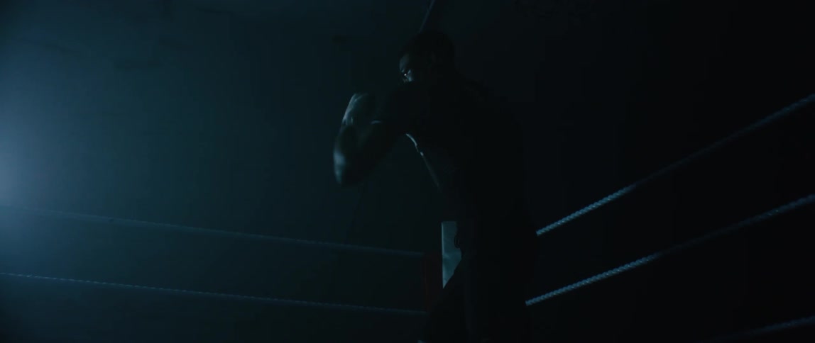 A male boxer practices throwing punches while standing in a boxing ring