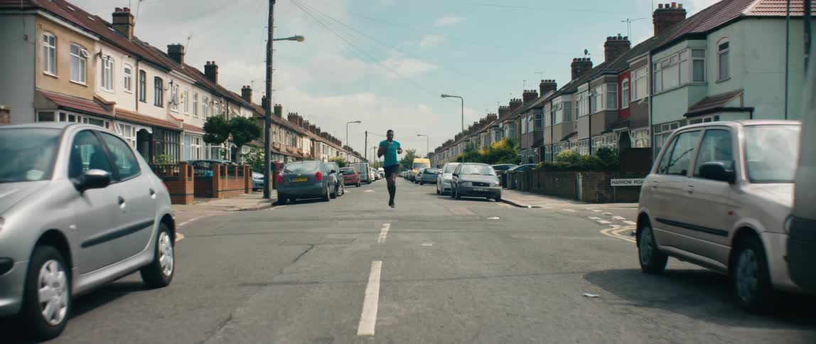 A man jogs down a street in a residential neighborhood during the day