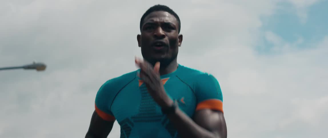 A man in athletic wear runs outdoors under a cloudy daytime sky