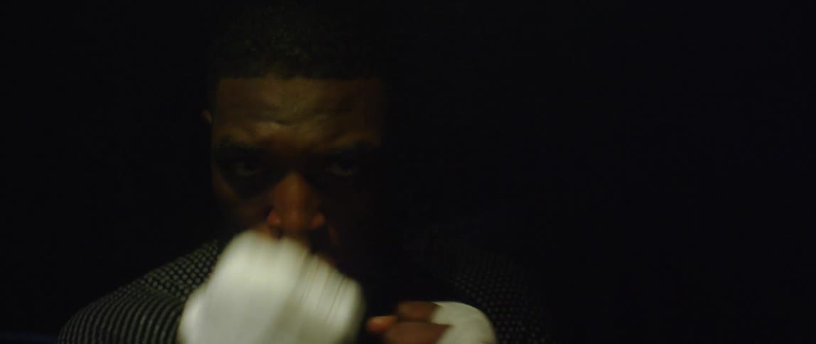 An athletic man throws numerous punches towards the camera as he practices boxing