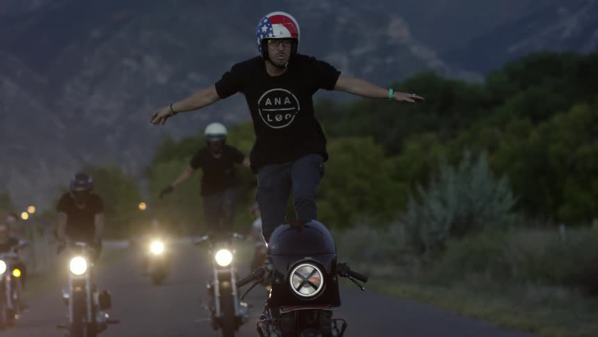 A group of people balance on their moving motorcycles