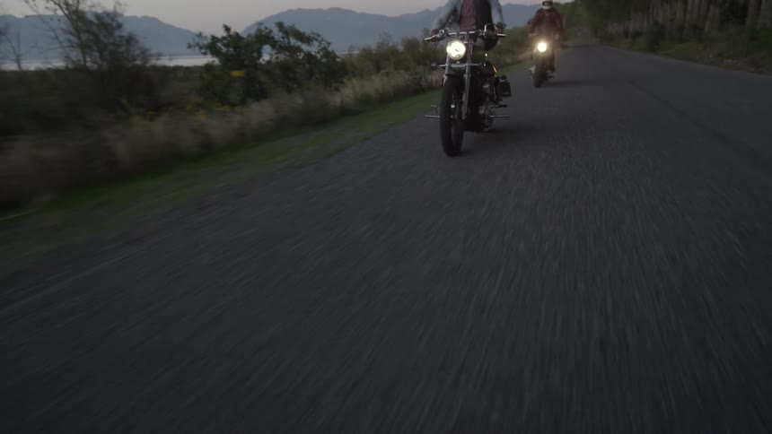 Two people ride their motorcycles on a cloudy day