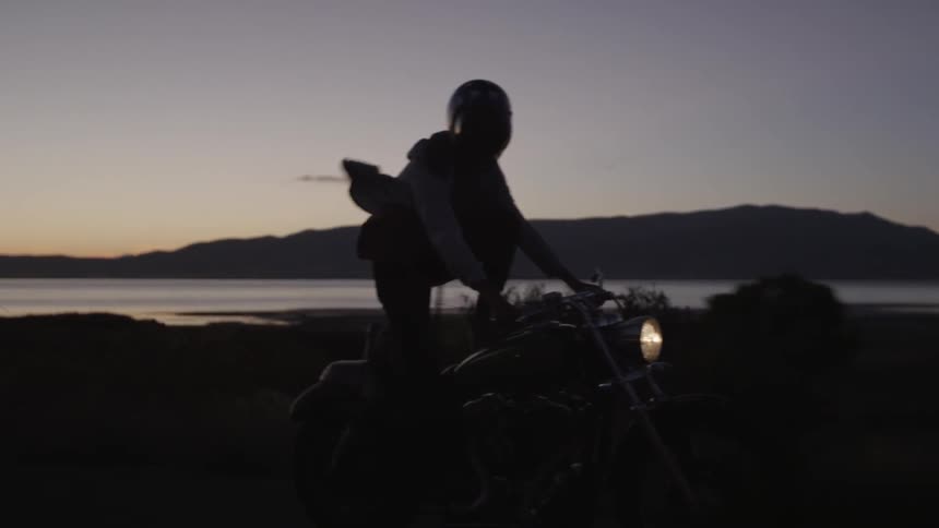A motorcycle driver rides with a foot on the gas tank