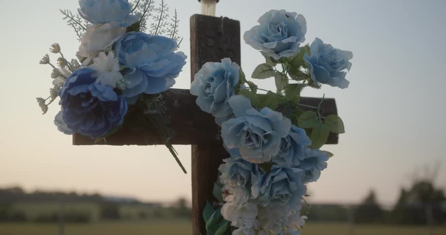Flowers are covering the cross grave marker