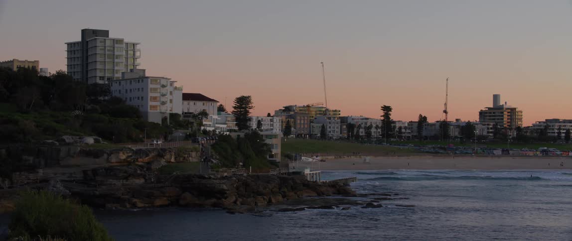 Waves roll into the beach area with hotels in the background at sunset