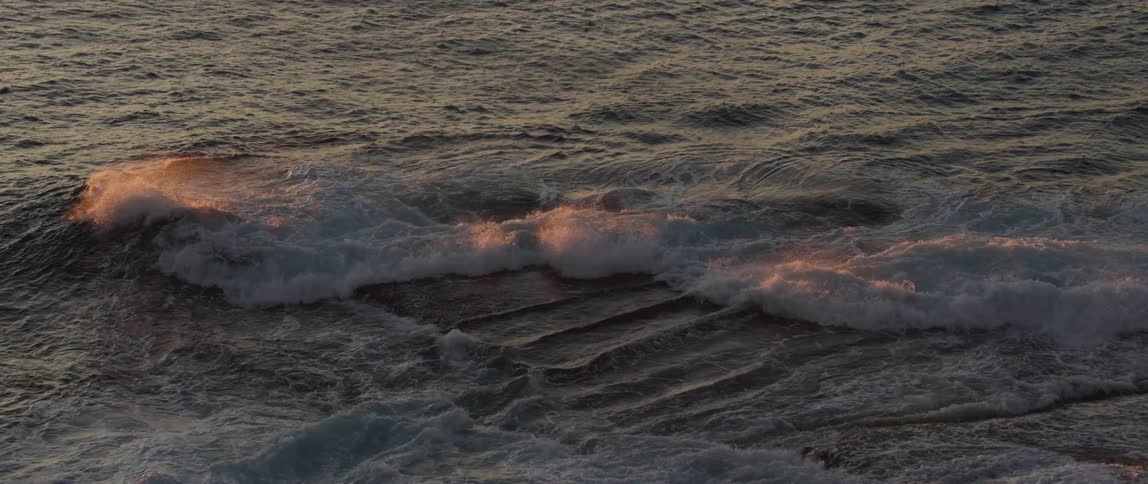 Sunlight shines on waves as they splash and roll into shore