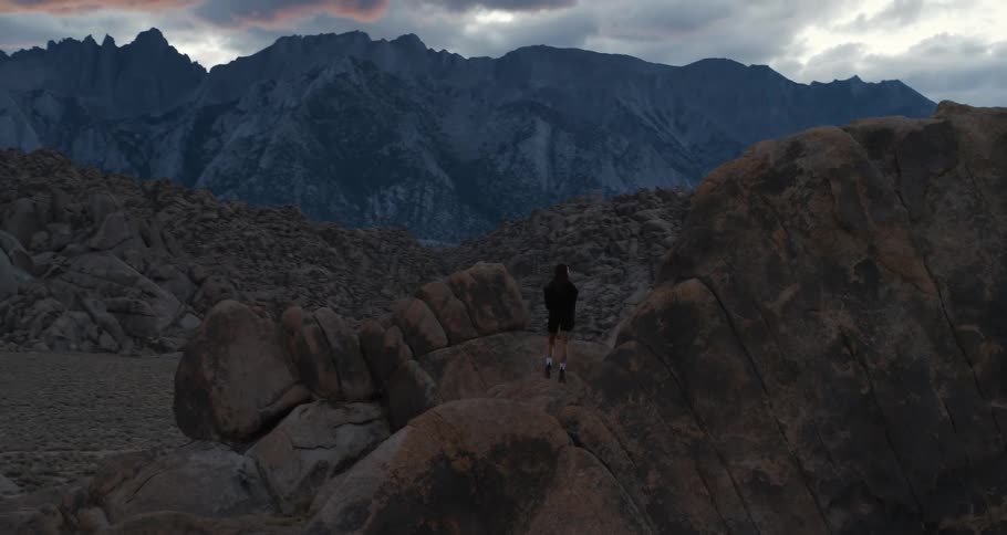 A female hiker stands at the base of Mt Whitney and takes in the view at sunset blue hour