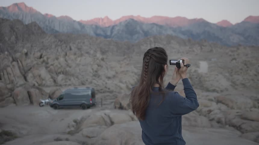 A woman is recording the mountains