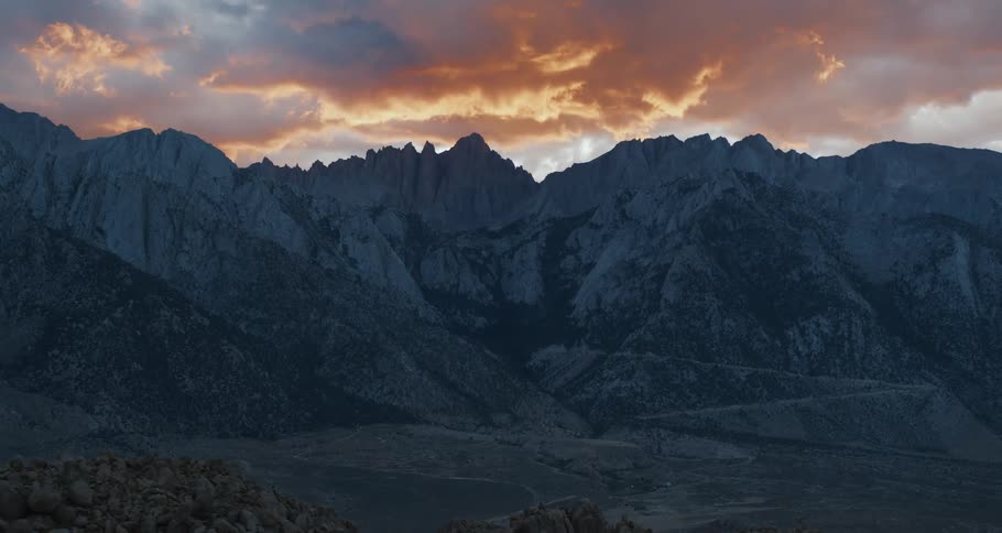 A jagged mountain ridge under a cloudy blue hour sky