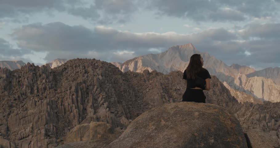 A woman sits atop a rock while looking out upon an amazing canyon