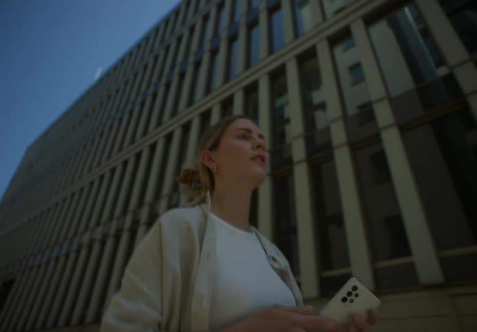 Blonde woman walking on the streets carrying a phone on her hand
