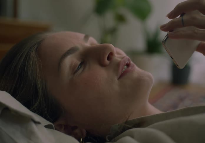 Woman lying on a pillow on the floor at home talking on her cellphone
