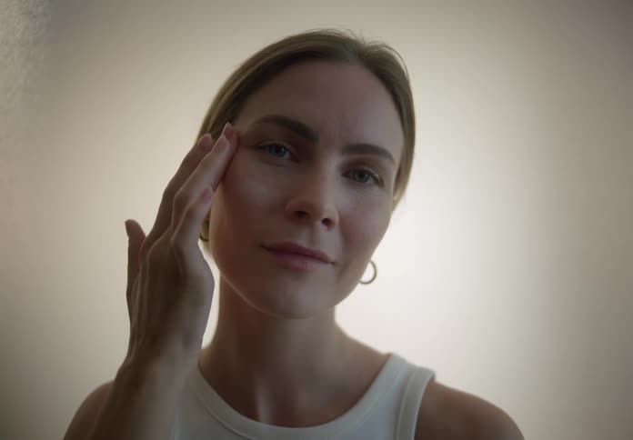 A woman applies moisturizer