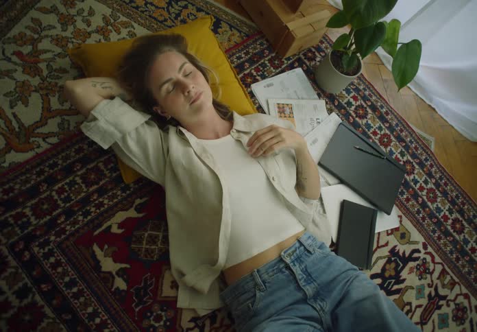 Woman lying down on a carpet on the floor next to notebooks and papers