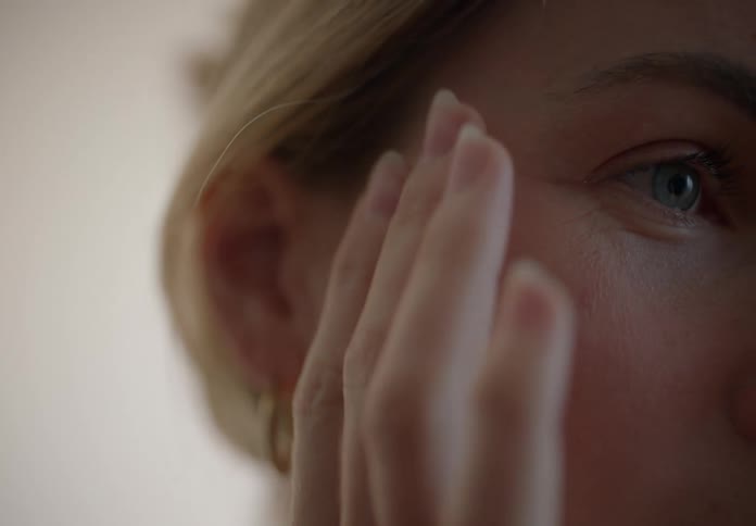 A woman rubs moisturizer on her face