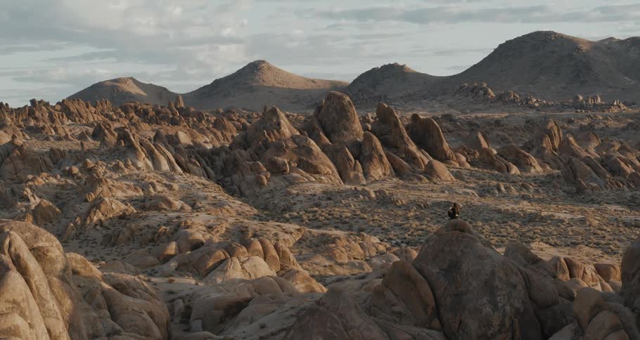 A woman is sitting on a huge boulder