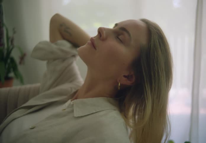 Woman relaxing in an armchair at home near the window tilting her head back and running her hand through her hair