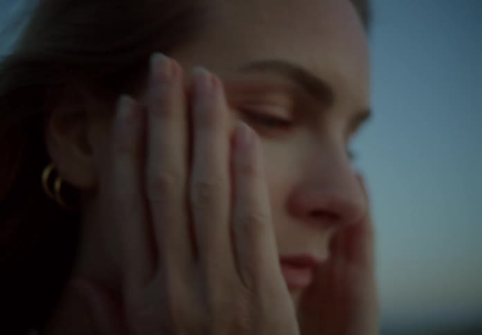 A woman rubs her face outside