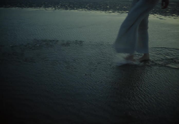 A woman splashes the water as she walks through