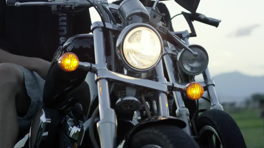 A man on a motorcycle lifts his glasses