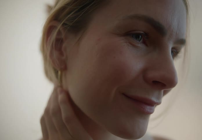 Blonde woman indoors caressing her face and neck