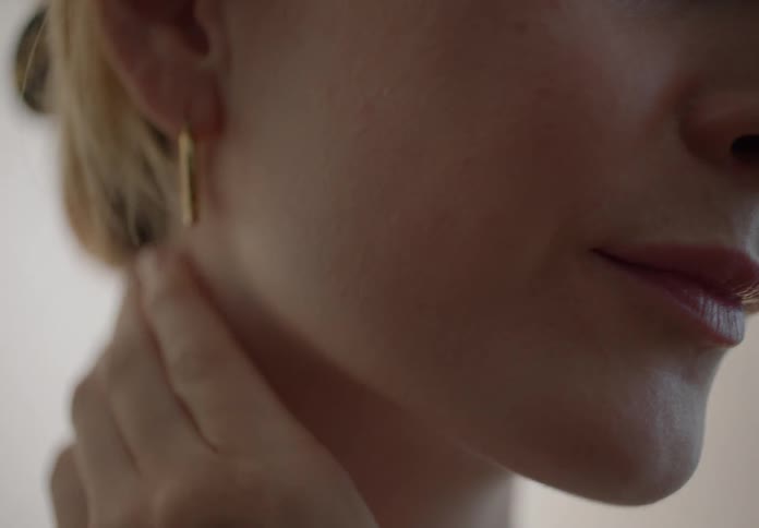 Blonde woman indoors massaging her face and her neck