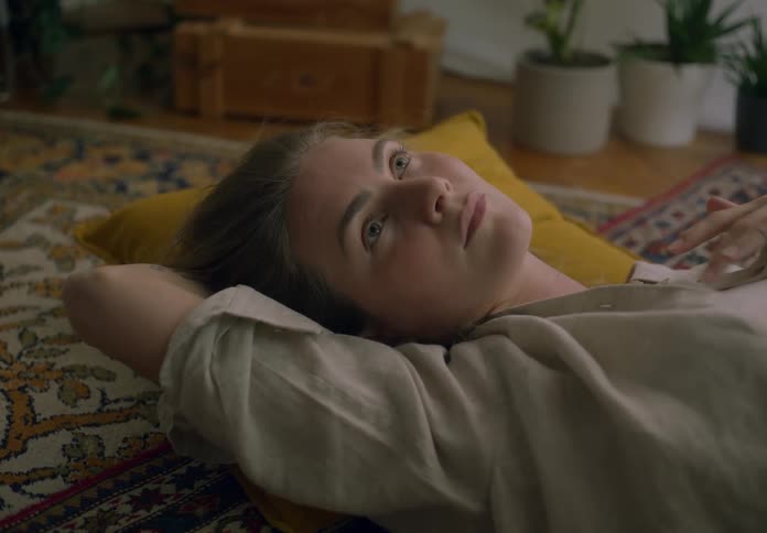 Blonde woman lost in thought lying down on the floor