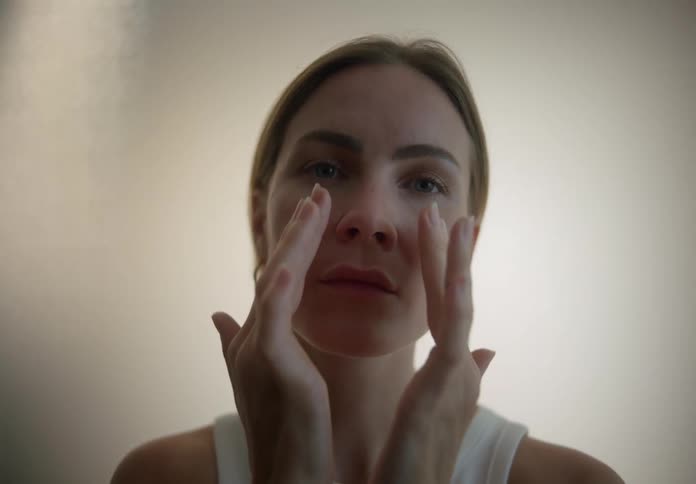 A woman puts moisturizer on her face