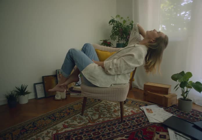 A woman sits sideways in a chair and leans her head back