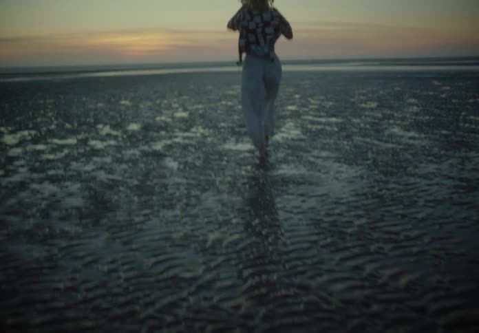Woman walking alone in a beach during dusk or dawn