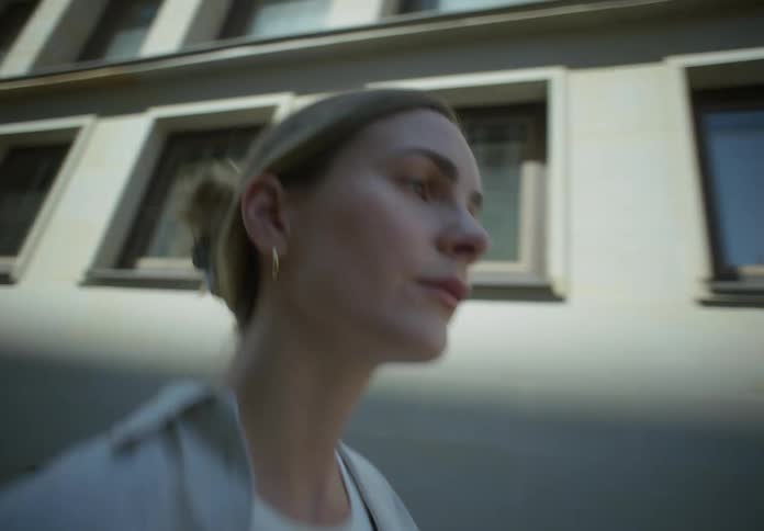 Blonde woman walking on the streets next to a big building