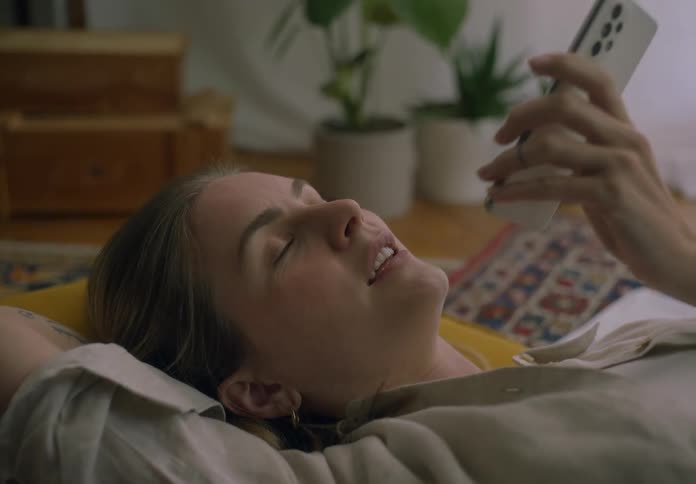 Woman lying on a cushion on the living room floor talking on the phone