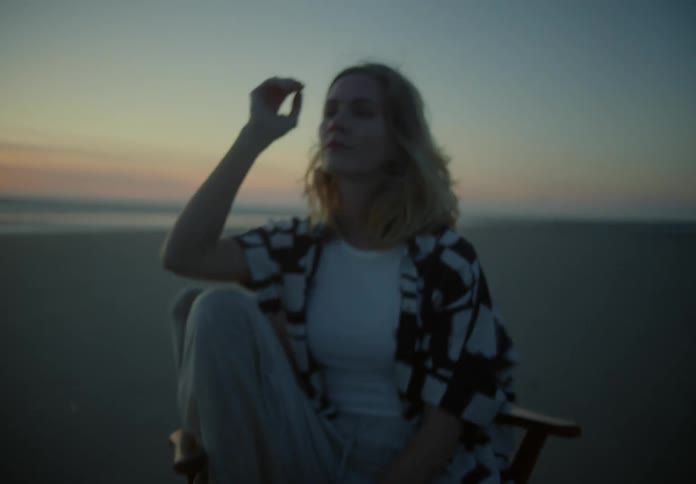A woman is sitting on the beach at sunset
