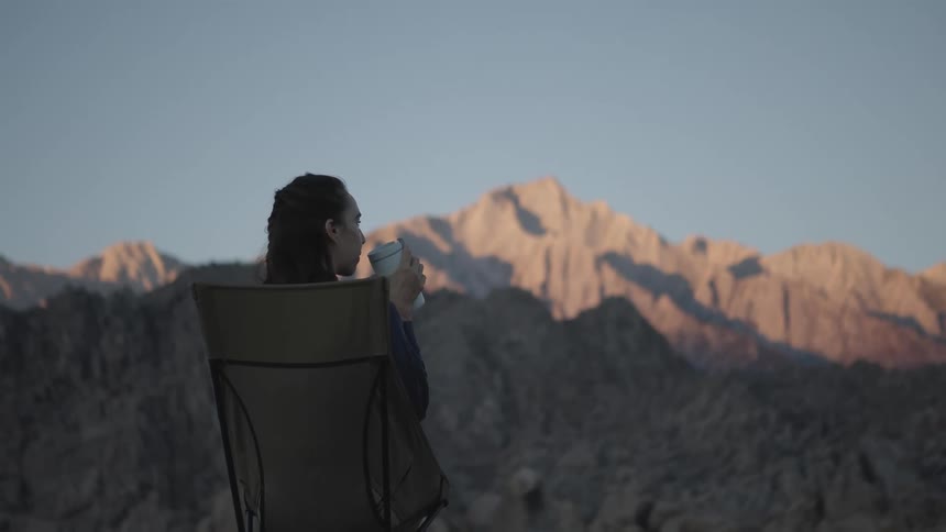 A woman camping drinks her morning coffee